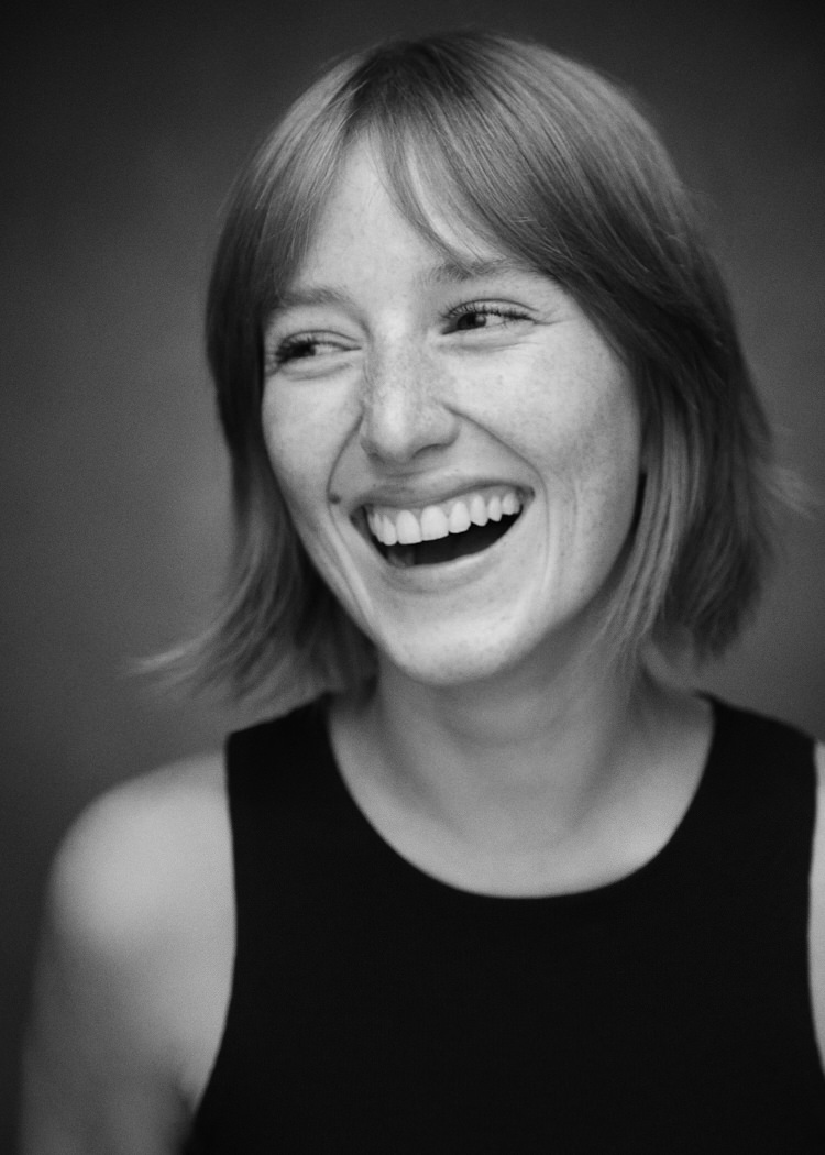 A black and white actors headshot of German actress Leah Lavinia. She is captured mid laughter in this heart warming candid image.